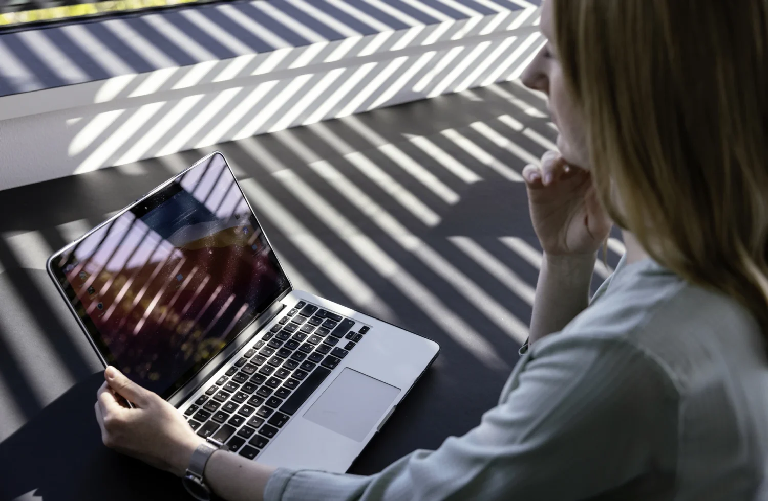 Person arbeitet am Laptop in einem sonnendurchfluteten Raum